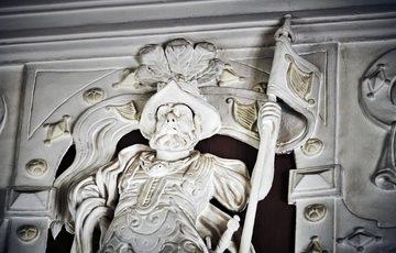 Ornate figure of a man in plaster on the ceiling.