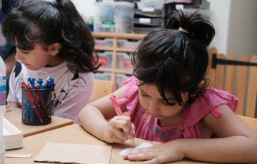 Children drawing while sitting at a table.