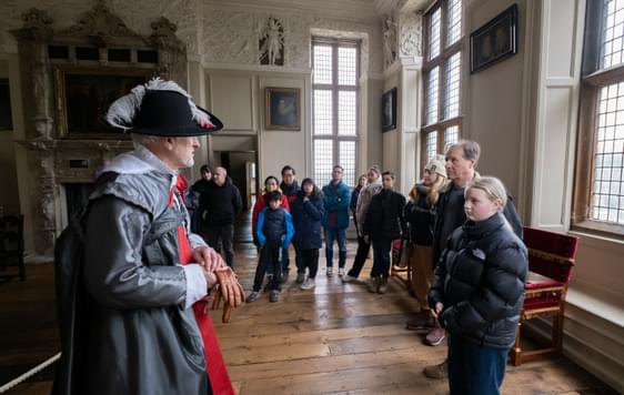 A tour guide dressed as Sir Thomas Holte giving a tour to a group of adults and children.