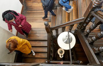 View looking down at people walking down an old historic wooden staircase.