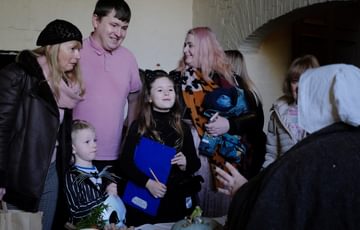 A family group talking to a staff member who is dressed in historic clothes.