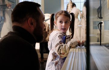 An adult and child looking into a display case.