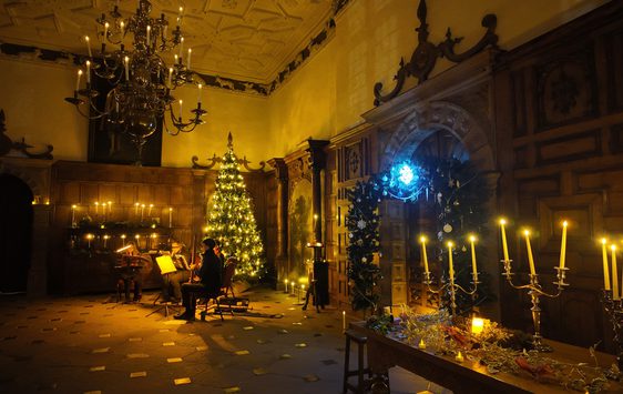 A dimly lit Great Hall decorated with candles and Christmas tree.