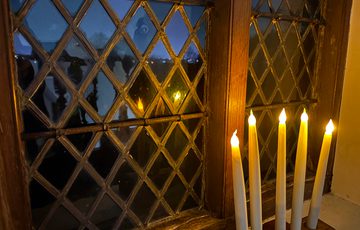 Candles on a windowsill against a historic window backdrop.