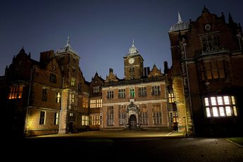 Illuminated historic mansion with intricate architecture against a dark night sky.