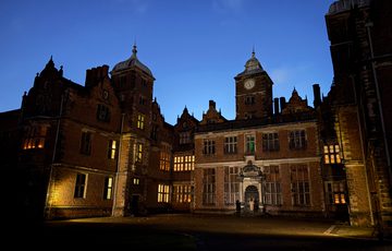 Historic mansion illuminated at night under a clear sky.