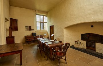 A simple dining room with fireplace and wooden tables and chairs.