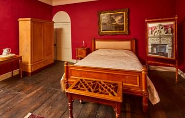 A red bedroom with wooden bed, wardrobe and other furniture.