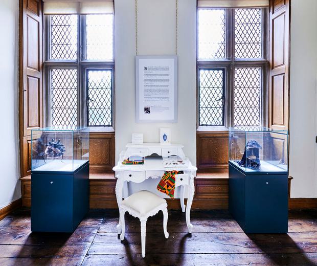 A room with two tall windows with a display case in front of each window and a dressing table in the middle.