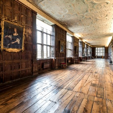 Jacobean wood-panelled Long Gallery with leaded windows and ornate plaster ceiling