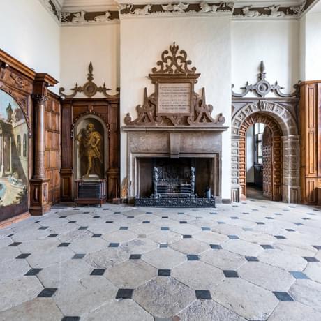 Large entrance hall with chequered stone floor and ornate fireplace
