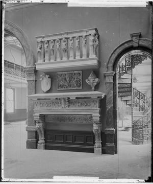 Black and white photograph of part of the gallery showing stonework objects on display in the centre of two arches.