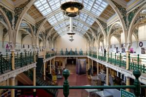 The Industrial Gallery balcony with ornate ironwork, gas lanterns hanging from a glazed ceiling.