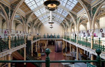 The Industrial Gallery balcony with ornate ironwork, gas lanterns hanging from a glazed ceiling.