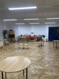A classroom space with chairs, tables and a display at the bottom.