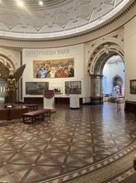 A round gallery space with large statue and paintings on display.