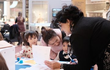 Adults and children looking at paper resource while doing a craft activity.