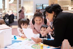 Adults and children looking at paper resource while doing a craft activity.
