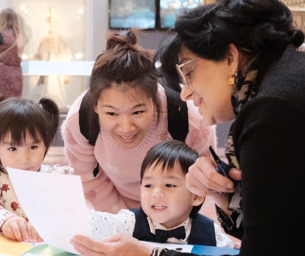 Adults and children looking at paper resource while doing a craft activity.