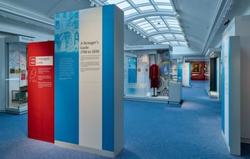An introduction to the gallery with display cases beyond, one of which contains a historic costume.