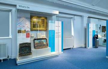 A display case featuring a japanned tray, painting and puppet show.