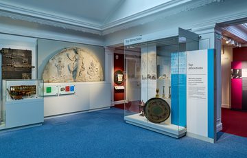 A wide angle of a display featuring a vairty of objects including a wooden door and stone carving.