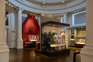 A circular room with display cases some of which contain historic dresses and costumes.