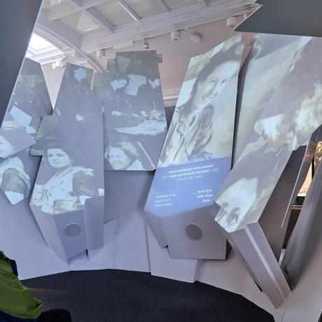 A person sitting watching a video on a large interactive piece made of fragments.