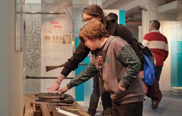 An adult and child touching an interactive tool bench.