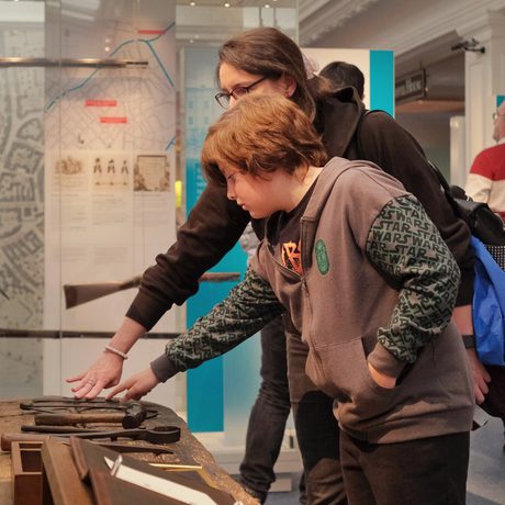 An adult and child touching an interactive tool bench.