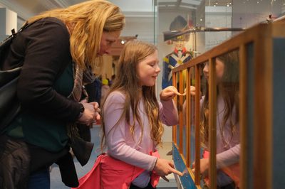 An adult and child looking into wood and glass interactive case.