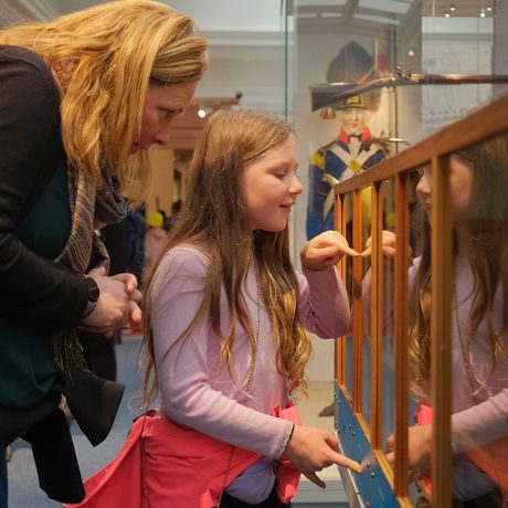 An adult and child looking into wood and glass interactive case.