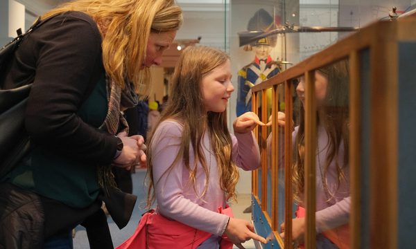 An adult and child looking into wood and glass interactive case.