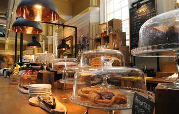 Café counter loaded with cakes under glass domes