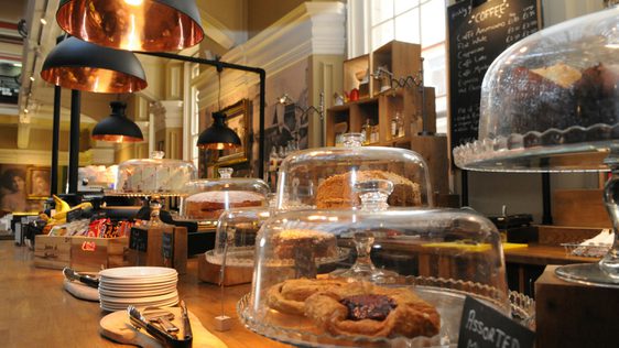 Café counter loaded with cakes under glass domes