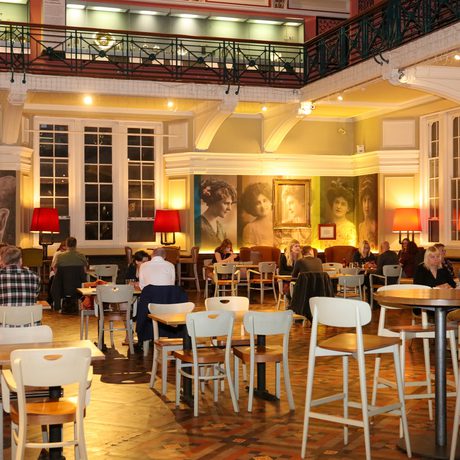 Tearoom with warm lighting, wooden furniture, and people engaged in conversation.