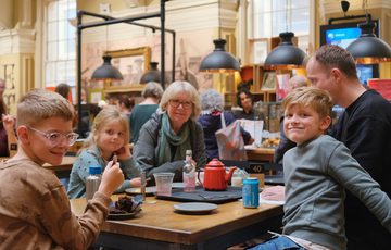 A smiling family sitting eating in a tearoom.
