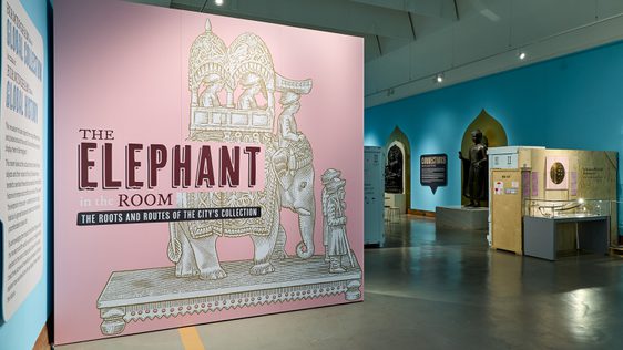 Large pink graphic signage that reads 'Elephant in the room display' with illustration elephant artefact.