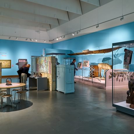 A wide shot of a gallery display featuring a range of display cases and objects.