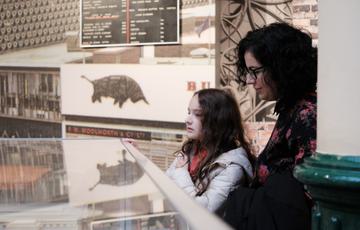 An adult and child looking at a object case.