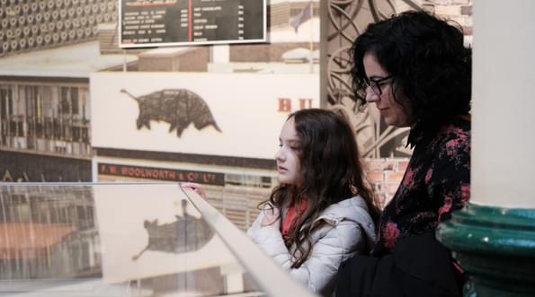 An adult and child looking at a object case.