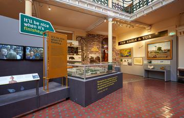 A display of objects relating to the city including a model of the city, sign from pub and artworks.