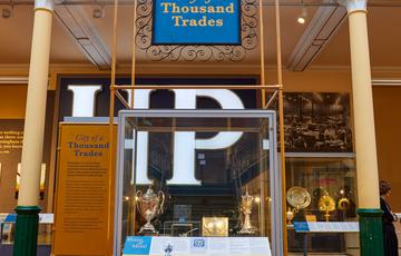 Sign that reads 'City of a Thousand Trades' along with a variety of objects from the metalwork collection with 'HP' sauce sign in the background..