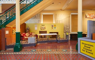 A display called 'Making Home' featuring a recreate lounge with sofa, fireplace, radiogram and photos on the walls.