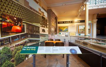 A display on redbuilding the bullring featuring a variety of photos and a cafe table as a centrepiece.