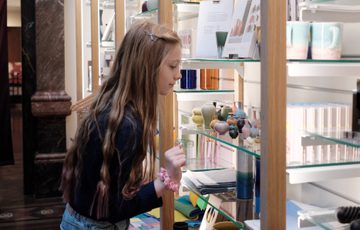A child looking a collection of small ceramic vases on display in the shop.