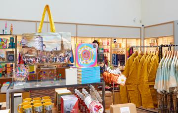 Shop items on display including Benny's Babbies Bag and Joe Lycett Art Hole book.