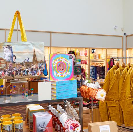 Shop items on display including Benny's Babbies Bag and Joe Lycett Art Hole book.