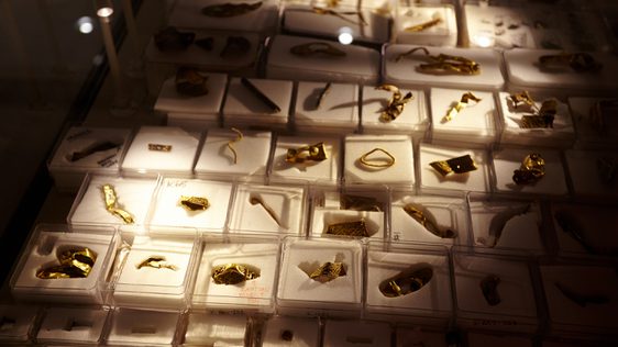 Close up of a large collection of Staffordshire hoard fragments in individual display boxes, the corners of the photo are dark with the artefacts highlighted in the centre.