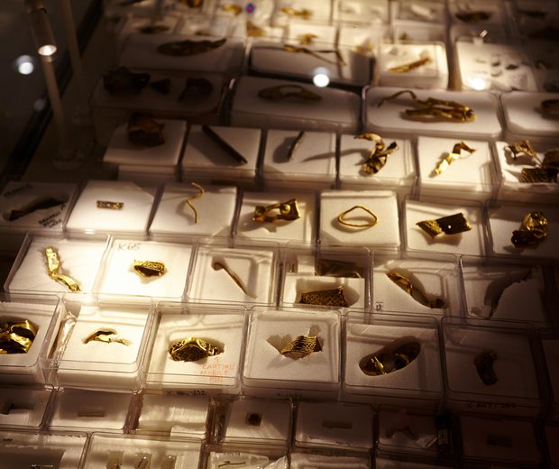 Close up of a large collection of Staffordshire hoard fragments in individual display boxes, the corners of the photo are dark with the artefacts highlighted in the centre.